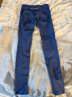 Blå seamless leggings från GTECH - Snygga blå seamless leggings från GTECH med hög midja och bred resår. De har en tight passform och är tillverkade i ett stretchigt material som formar kroppen bra💓Perfekt för träning. Obs det är en liten fläck framtill (se sista bilden) men den syns knappt🩷 Säljer för att dom inte passar mig längre, nypris: 500 kr