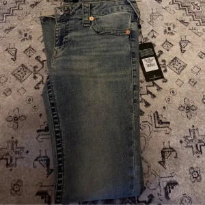 True Religion Flared Jeans - Säljer ett par blåa True Religion  jeans med låg midja och utsvängda ben. Säljer dessa då dem var för stora på mig och är helt nya med tagg på! Köptes för ca 1200kr. pris kan diskuteras