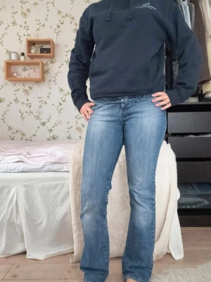 Blå bootcut jeans med broderi - Säljer ett par blå bootcut jeans med snyggt broderi på bakfickorna. Jeansen har en klassisk femficksmodell och lätt slitna detaljer framtill. Perfekta för dig som gillar en avslappnad men ändå trendig look. Priset går att diskuteras vid snabb affär!