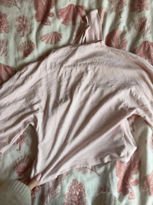 Ljusrosa croppad polotopp - Söt ljusrosa croppad polotopp med lång ärm. Tillverkad i mjukt bomullsmaterial som känns skönt mot huden. Perfekt att styla med höga jeans eller kjol för en trendig look.