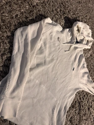 Vit hoodie från Polo Ralph Lauren🙌🤩 - Säljer en stilren vit hoodie från Polo Ralph Lauren i mjukt, ribbat bomullstyg. Hoodien har huva med dragsko, känguruficka och den klassiska lilla broderade loggan på bröstet. Perfekt för en avslappnad och trendig look.