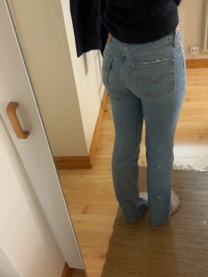 Ljusblå bootcut jeans från Levi's - Säljer ett par klassiska ljusblå jeans från Levi's med bootcut ben och normal midja. Jeansen har fem fickor, bälteshällor och är tillverkade i denim. Perfekta för en avslappnad och trendig look. Storlek 23 men passar XS. Är 165 som referens