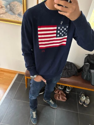 Ralph lauren stickad med amerikansk flagga  - En riktigt fet Ralph lauren stickad tröja som er amerikansk flagga på bröstet som är riktigt fet.  Den är i storlek M och modellen på bilden är 186 och väger 68kg Den är bara använd in en vecka och är i riktigt bra skick. Priset är inte fast! Skriv vid funderingar 😁