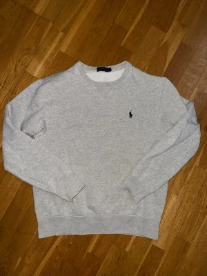 Grå sweatshirt från Polo Ralph Lauren. Storlek S. - Klassisk ljusgrå sweatshirt från Polo Ralph Lauren med rund halsringning och broderad marinblå logga på bröstet. Storlek S. Nypris var cirka 1300kr.