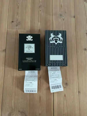Creed Aventus & Parfums de Marly parfym reseller bundle - Två exklusiva parfymer: Creed Aventus i svart rektangulär förpackning med silverdetaljer och Parfums de Marly Royal Essence i svartvit randig box med vita hästar och logotyp. Båda dofterna är populära inom lyxsegmentet och kommer i eleganta förpackningar.