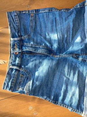 Gina jeans shorts - Säljer ett par klassiska blå jeansshorts. De har uppvikta benslut och dragkedja med knapp. Perfekta för sommaren och har en snygg tvättad denimlook.