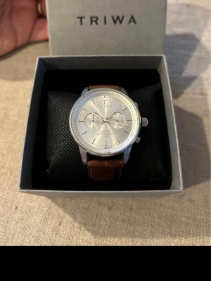 Triwa Nevil 42mm Herrklocka - Säljer en snygg stilren herrklocka från svenska Triwa i fint skick. Finns en skada i glaset. Fungerar bra, äkta läderarmband (ej org.), datumvisare, vattentät, kronograf osv. Behöver bara nytt batteri. Fås i original klocklåda.  Nypris: 2700 SEK Begagnat pris: 1000 SEK Mitt pris: 489 SEK  Skickas alltid snabbt och spårbart (ofta samma dag) eller hämtas i Glumslöv.  Hör av dig vid frågor och se gärna mina andra annonser också!   Case size: 42 mm Style: Chronograph Case Material: Stainless steel S