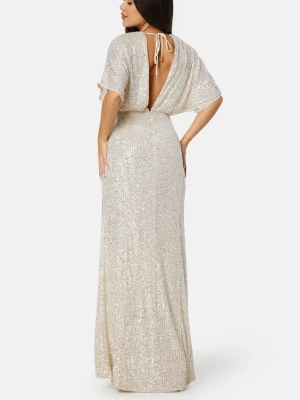 Glittrig långklänning med öppen rygg - Elegant långklänning i ljus champagnefärg med glittrigt material. Klänningen har v-ringning, vida korta ärmar och en snygg öppen rygg med knyt i nacken. Perfekt för dig som vill sticka ut på balen!