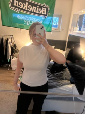 Vit ribbad topp med hög hals - Säljer en stilren vit ribbad topp med hög hals och korta ärmar. Toppen har en figurnära passform och är gjord i ett stretchigt material som sitter snyggt på kroppen. Perfekt att matcha med både jeans och kjol.