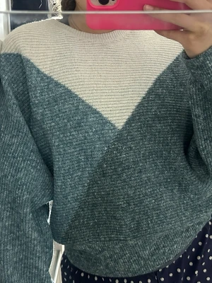 Stickad tröja med färgblock - Mysig stickad tröja med breda färgblock i vitt och blågrönt. Tröjan har rund halsringning och avslappnad passform med långa ärmar. Perfekt för dig som gillar en enkel men snygg stil.