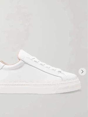 Vita sneakers från Chloé  - Stilrena vita sneakers från Chloé i slätt läder med vågig detalj längs sulan och svart hälflik med logotyp. Klassisk låg modell med vita skosnören och mjuk innersida i beige. Perfekta för en clean och modern look. Nypris ligger på ca 6000 och de är knappast använda då jag köpte en för liten storlek.🥰