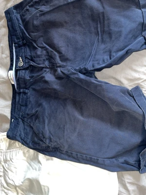 Mörkblå bomullsshorts från Jack and Jones  - Snygga mörkblå shorts från Jack and Jones  i mjuk bomull. Klassisk design med knapp och dragkedja framtill, samt fickor både fram och bak. Perfekta för varma dagar och enkel att matcha med olika stilar.