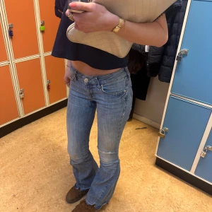 Ljusblå bootcut jeans med låg midja - Säljer ett par ljusblå bootcut jeans med låg midja. De är slitna och vintage. I storlek XS-S. Har en del slitningar men är fortfarande supersnygga. 