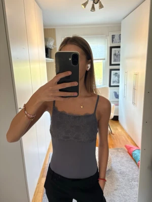 Grå body med spets  - Grå body med tunna axelband och spets över bysten. 