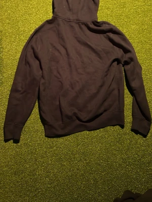 Svart hoodie från Polo Ralph Lauren - Klassisk svart hoodie från Polo Ralph Lauren med huva och ribbade muddar. Tillverkad i mjukt bomullsmaterial som känns skönt mot huden. Perfekt för dig som gillar en enkel och stilren look.
