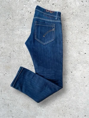 Mörkblå jeans från dondup - Mörkblåa jeans från dondup i model George med raka ben och klassisk femficksdesign. Jeansen har kontrastsömm support och knappgylf. Materialet är slitstark denim i bomull. Perfekta för dig decla gillar en enkel och tidlös look.