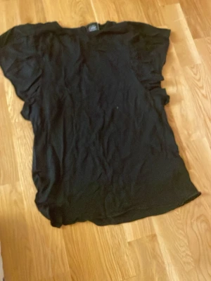 Svart t-shirt från Petit Sore Schnorr - En klassisk svart t-shirt från Petit Sore Schnorr. T-shirten har en enkel design med rund hals och korta ärmar. Perfekt basplagg att matcha med olika outfits.