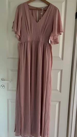 Ljusrosa långklänning/balklänning  - Säljer en  ljusrosa långklänning/balklänning från Bubbleroom. Klänningen har  v-ringning och volangärmar samt  ett markerat midjeparti och ett luftigt, fallande tyg som ger en romantisk känsla. Perfekt för speciella tillfällen. Helt ny, ej använd. Stl 36. 