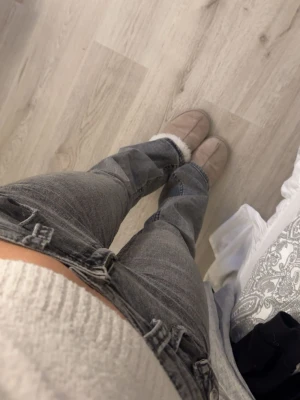 Grå bootcut jeans med hög midja - Säljer ett par grå bootcut low waist jeans. Jeansen har dubbla knappar i linningen och klassisk ficksdesign. Materialet är denim med en lätt tvättad look. Perfekta till en avslappnad stil.