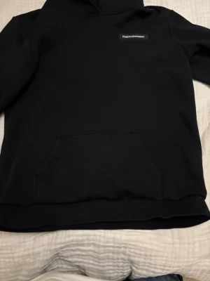 Svart Peak Performance hoodie - Säljer en svart hoodie från Peak Performance med klassisk logga på bröstet. Hoodien har en stor känguruficka framtill och en skön huva. Perfekt för dig som gillar enkel och stilren design. Materialet känns mjukt och bekvämt. Hör av er vid mer info storlek 170! 