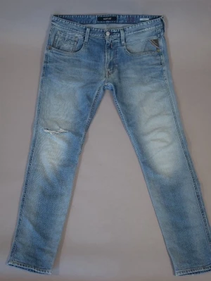 Ljusblå Replay Anbass med slitningar - 📏: W34 L32.                                         ⭐️:4,2/5.                                                           🐑:98% bomull 2% elastan.                       Säljer ett par ljusblå jeans från Replay med skinny fit och slitning på vänster lår. Klassisk femficksmodell med dragkedjegylf och snygg tvättad look. Perfekta för dig som gillar en avslappnad och trendig stil.