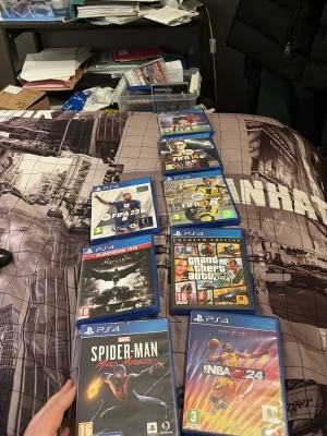 PS4 spelpaket med 8 spel och 2 ps 4 kontroller  - Säljer ett paket med 8 PS4-spel: FIFA 23, FIFA 21, FIFA 14, FIFA 17, Grand Theft Auto V Premium Edition, Batman Arkham Knight, Marvel's Spider-Man Miles Morales och NBA 2K24. Alla spel är i blå plastfodral och passar till PlayStation 4. Perfekt för dig som gillar sport, action och äventyr. Plus det kommer med 2 kontroller 