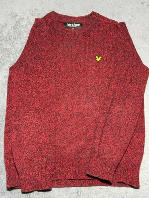 Lyle & Scott Knit Sweater – Red / Black – Size S - Stickad tröja från Lyle & Scott i röd/svart melerad färg.  Klassisk modell med rund hals och den ikoniska golden eagle-loggan på bröstet.  Perfekt för höst och vinter och passar bra till både jeans och chinos.  Detaljer • Lyle & Scott • Stickad tröja • Röd / svart melerad • Broderad logga • Storlek S  📦 Skickas snabbt 💬 Hör av dig vid frågor
