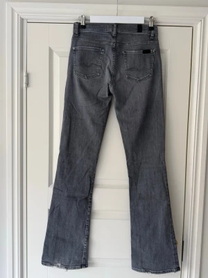 7 FOR ALL MANKIND Bootcut Jeans - Tidlösa grå bootcut jeans från 7 For All Mankind i storlek W26. Fint, använt skick! Så snygga till alla tillfällen. Nypris låg runt 2600 kr.