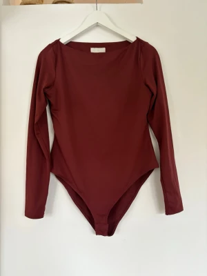 Vinröd långärmad body - En vinröd body med långa ärmar och båtringning Storlek M, gott skick. Knäpps nertill🤗
