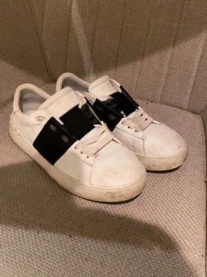 Vita sneakers från Valentino med svart band - Jag säljer nu mina Valentinos då dem ej kommer till användning. Dem är inte använda mycket alls så dem är i bra skick. Skorna är äkta, kvitto och låda tillkommer🙏