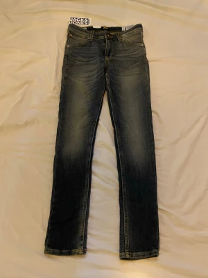 Blå skinny jeans från Jack & Jones - Snygga blå skinny jeans från Jack & Jones med klassisk femficksdesign och diskreta slitningar. Jeansen har normal midja och smal passform som sitter tajt längs benen. Perfekta till en avslappnad och trendig stil.