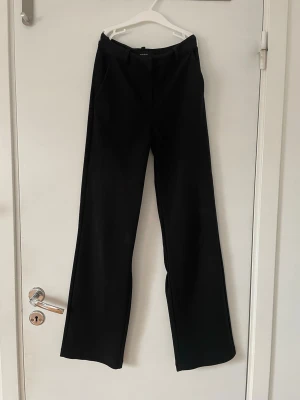 Svarta kostymbyxor  - Snygga svarta kostymbyxor från Vero Moda med raka ben och medelhög midja. Byxorna har diskreta sidfickor och är sydda i skrevet för en bättre passform.
