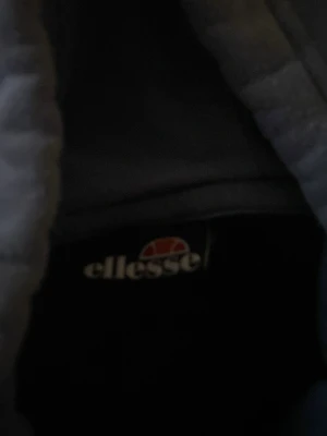 Blå Ellesse hoodie med logga - Snygg hoodie från Ellesse i två nyanser av blått med stor logga framtill. Klassisk huva med dragsko och magficka. Perfekt för en avslappnad och sportig stil. Mjuk bomullsblandning som är skön att ha på sig.