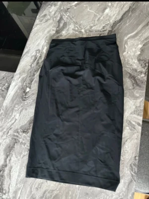 Svart kjol i storlek m  - Kjolen har hög midja och är designad för att forma och släta ut siluetten. Perfekt under klänningar eller kjolar för en smickrande look. Inga synliga sömmar framtill för en diskret finish.