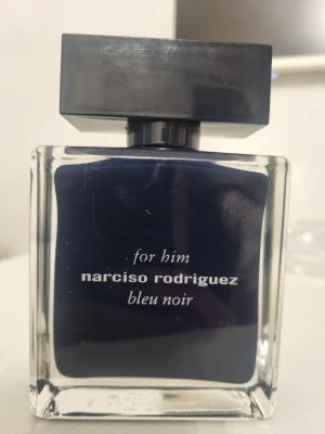 Narciso Rodriguez Bleu Noir Parfym - Snygg herrparfym från Narciso Rodriguez, modellen Bleu Noir. Flaskan är rektangulär i glas med mörkblå insida och svart fyrkantigt lock. Modern och stilren design som passar perfekt på hyllan.