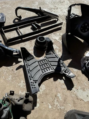 Diverse mopeddelar i svart plast och metall - Ett gäng olika mopeddelar säljes, bland annat en svart plastmatta med mönster, avgassystem i metall, ramdelar och kåpor. Perfekt för dig som mekar med mopeder och behöver reservdelar eller vill bygga eget.
