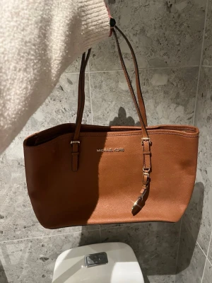 Brun handväska  - Snygg och stilren michael kors tote handväska, använd några gånger då den är köpt ett par år sedan. 