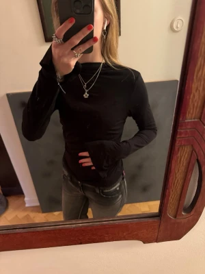 Svart långärmad topp från Gina Tricot - En enkel svart långärmad tröja i mjukt och tunt material. Perfekt som basplagg och lätt att matcha med olika stilar. Tröjan har rund hals som går upp lite, men inte som en polo, och tajt kring midjan med trekantiga armar. Jättesval och skön att ha på sig! Storlek M men passar S. 