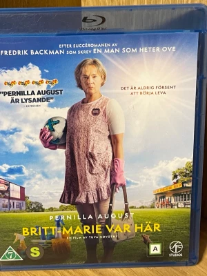 Britt-Marie var här Blu-ray - Svensk dramakomedi baserad på Fredrik Backmans roman. Filmen handlar om Britt-Marie som efter ett långt äktenskap börjar om på nytt i småstaden Borg. Omslaget är blått med en bild på huvudkaraktären i rosa klänning, fotboll och städutrustning. Text på svenska.