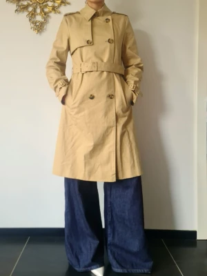 Helt ny Beige klassisk trenchcoat med bälte från MANGO - Helt ny trenchcoat från MANGO .  Storlek: S     färg: Beige   Säljer den pga gillar inte färgen