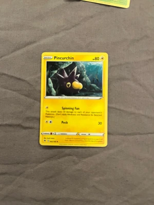 Pokémonkort Pincurchin - Säljer ett Pokémonkort med motivet Pincurchin. Kortet har en gul ram och färgstark illustration av Pincurchin i undervattensmiljö. Text och detaljer är tryckta på engelska. Perfekt för samlare eller Pokémonfans.