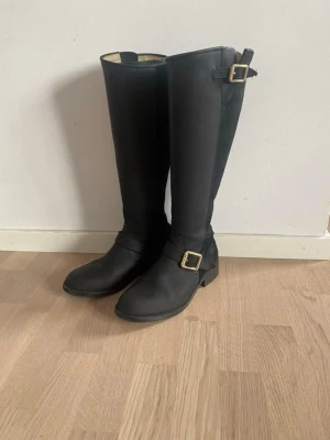 Urban Project Harley Stövlar 38 - Urban Project Harley Stövlar Zip Svart storlek 38 Väldigt sparsamt använda, så i väldigt bra skick! Knähög stövel från Scorett. Dekorativa spännen och zip baktill Skafthöjd 41 cm Klackhöjd 3 cm