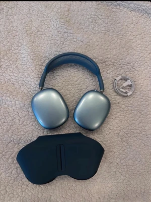 Blå Apple AirPods Max hörlurar - Snygga blå Apple AirPods Max med mjuka öronkuddar och justerbart huvudband i mesh. Hörlurarna har en stilren aluminiumdesign och kommer med matchande fodral och laddkabel. Perfekta för dig som vill ha grymt ljud och modern look.
