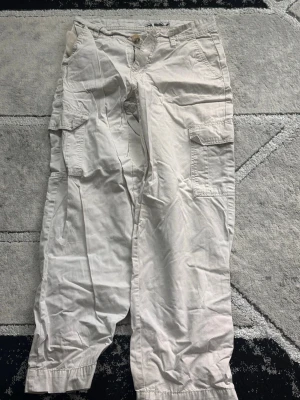 Beiga cargobyxor med fickor - Snygga beiga cargobyxor med flera stora fickor på sidorna och klassisk cargomodell. Byxorna har raka ben. Perfekta för dig som gillar streetwear och praktiska detaljer.