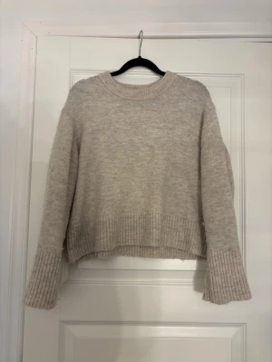 Beige stickad tröja Gina Tricot - Mysig beige stickad tröja från Gina Tricot. Tröjan har en avslappnad passform. Materialet känns mjukt och skönt mot huden.