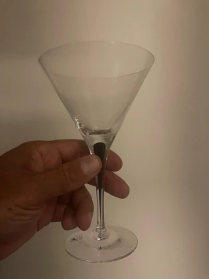 Klassiskt martiniglas i glas - Säljer ett stilrent martiniglas med bred, konformad kupa och smal fot. Glaset är helt transparent och har en elegant form som passar perfekt för drinkar som martini eller cosmopolitan. Perfekt till hemmabaren eller som present.