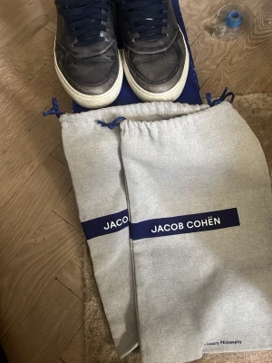Jacob Cohen sneakers - Ett par snygga mörklå sneakers i skinn/mocka från Jacob Cohen! Storlek 42. De är sparsamt använda och 2 dustbags samt box ingår vid köp. Skriv vid minsta lilla fundering eller behov av fler bilder!