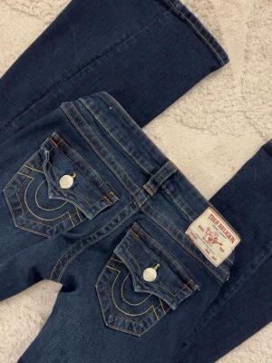 Mörkblå true religion jeans  - Säljer ett par mörkblå True Religion jeans i modellen JOEY Low Rise Flare i storlek 23. Använt ca 2 gånger och ser helt nya ut förutom en jätte lite slitning längst ner vid fötterna men det syns inte när man har på sig dom (se bild 4)