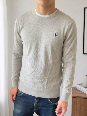 Ralph Lauren ljusgrå tröja  - Säljer en sjukt fet tröja från Ralph Lauren i färgen ljusgrå. Tröjan är i bra skick då den har varit väl omhändertagen, förutom att nacklappen tyvärr har trillat av. Tröjan är i strl M och sitter även som M. Hör gärna av er vid frågor elr funderingar!! 