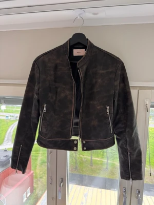Vintage wash skinnjacka - Mörkbrun skinnjacka med snygg vintage wash-effekt som skiftar mot svart i olika ljus. Croppad modell med silverfärgade detaljer som ger en cool och tidlös look. Fint skick🤎🖤